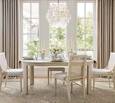 a dining room table with four chairs and a chandelier hanging from the ceiling