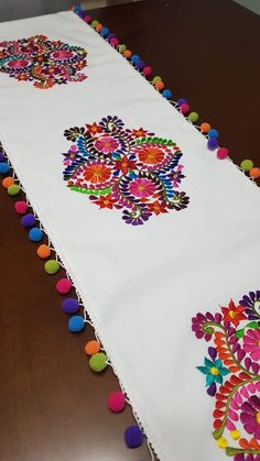 an embroidered table runner with pom - poms on the edge and colorful flowers