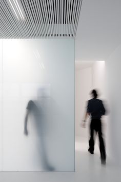 a blurry image of a man walking in front of a white wall with lines on it