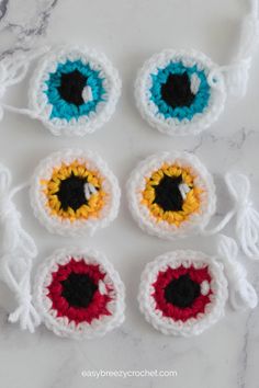 crocheted eyeballs are arranged on a marble surface