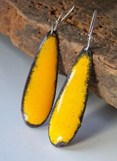 two yellow and black earrings sitting on top of a piece of wood