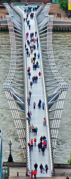 people walking across a bridge with umbrellas over their heads