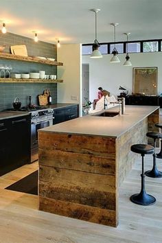 a kitchen with an island, stove and sink in the center is surrounded by wooden shelves