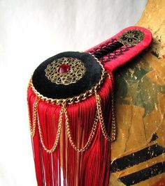 a red and black decorative object with chains around it's neck, sitting on top of a rock