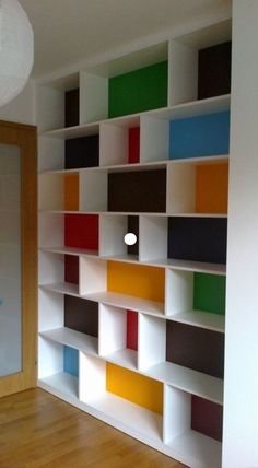 an empty room with colorful bookshelves on the wall and wood flooring in front of it