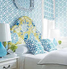 a bedroom with blue and yellow wallpaper, white bedding, and two lamps