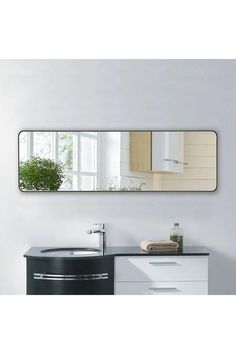 a bathroom with a sink, mirror and plant on the counter top in front of it