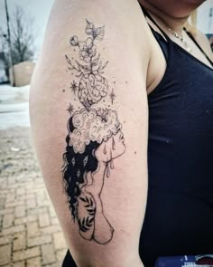 a woman's arm with a tattoo on it that has flowers growing out of her head