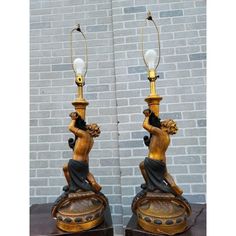 a pair of lamps that are sitting on top of a wooden table in front of a brick wall