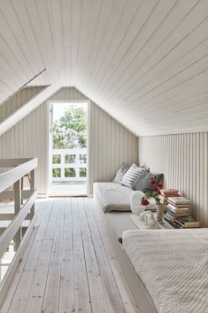 an attic bedroom with white walls and wooden floors