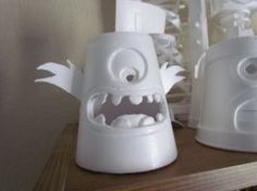 two white plastic objects with eyes and mouths on top of a wooden shelf in front of a mirror