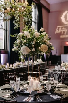 a tall centerpiece with white flowers and greenery sits on top of a round table