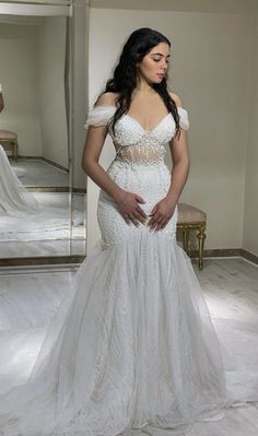 a woman in a wedding dress looking at herself in the mirror with her hands on her hips