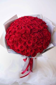 a bouquet of red roses wrapped in white paper