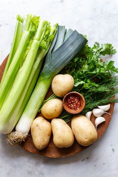 vegetables are arranged on a wooden platter, including celery and potatoes