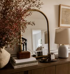 a table with a mirror, lamp and vase on it in front of a dresser