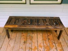 a wooden bench sitting on top of a hard wood floor next to a building with two windows