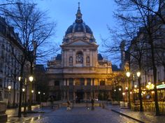 an old building is lit up at night in the middle of a cobblestone street