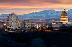 the city is lit up at night with mountains in the background