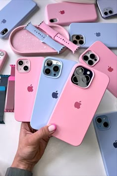 a person holding an iphone case in front of several different colors of cases on a table