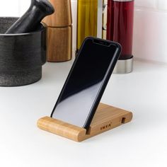 a cell phone sitting on top of a wooden stand in front of some cups and containers