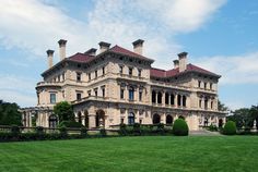 an old style mansion with many windows and balconies on the top floor, surrounded by lush green grass