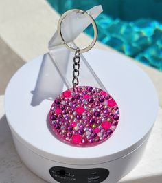 a keychain with pink and purple beads hanging from it's holder next to a swimming pool