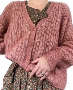 a woman wearing a pink cardigan sweater and floral print dress with her hands in her pockets