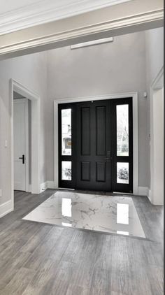 an empty room with a black door and white trim on the walls is pictured in this image