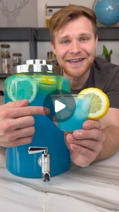 a man holding up two glasses with lemons and blue liquid