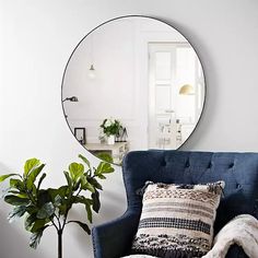 a living room with a blue chair and round mirror