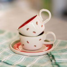 two cups and saucers are stacked on top of each other, sitting on a plate