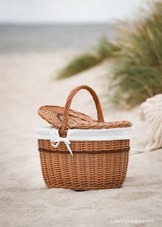 a wicker basket sitting on top of a sandy beach