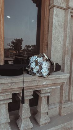 a bouquet of flowers sitting on top of a stone bench in front of a window