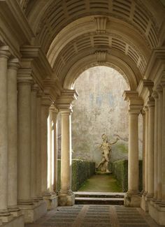 an archway leading to a statue in the middle of a room with columns and arches