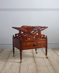 an antique wooden box with ornate carvings on the lid and legs, sitting on a wood floor