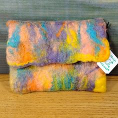 two colorful felted items sitting on top of a wooden table next to each other