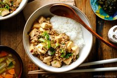 two bowls filled with rice, meat and veggies next to chopsticks