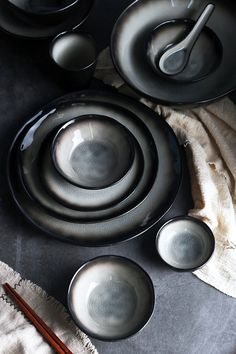 a table topped with black dishes and chopsticks