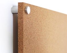 a close up of a cork board with holes in the middle and a white wall behind it