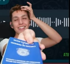 a young man holding up a blue book