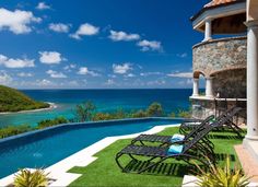 an outdoor swimming pool with chaise lounges on the lawn overlooking the ocean and hills