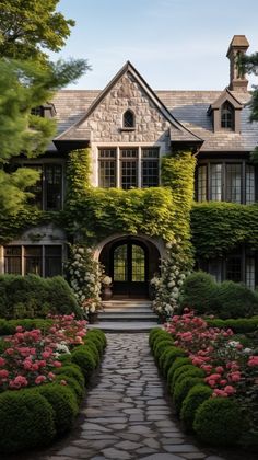 a large house with lots of flowers and greenery on the front door, surrounded by hedges