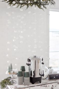 a coffee maker sitting on top of a white table next to christmas decorations and candles