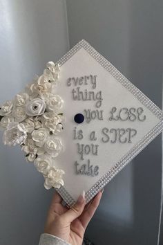 someone is holding up a graduation cap decorated with white flowers and the words, every thing you