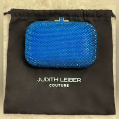 Meet A Clutch With Real Icon Status. Our Oval-Shaped Slide Lock Clutch Dazzles In Full Handset Crystal And Is Ready For Its Close Up On The Red Carpet, At The Gala Or Simply On A Spectacular Saturday Night. This Model Is For Sale On The Judith Leiber Website In Other Colors. - Encrusted With Blue Faceted Crystals - Special Edition Color: Capri Blue - Silver Toned Metal Hardware - Sliding Closure With Crystals - Metallic Leather Interior - Removable Silver Chain - Imported - Includes: Judith Leib Luxury Blue Pouch Clutch, Designer Blue Evening Bag, Luxury Blue Rectangular Clutch, Luxury Blue Bag For Events, Blue Clutch Evening Bag With Dust Bag, Blue Luxury Evening Bag With Removable Pouch, Blue Clutch With Removable Pouch For Party, Luxury Blue Evening Bag With Removable Pouch, Blue Party Clutch With Removable Pouch