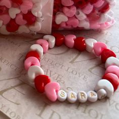 a couple of bracelets sitting on top of a table next to some candy hearts