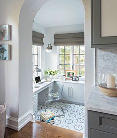 an archway leads to the kitchen and dining area in this modern, white - walled home