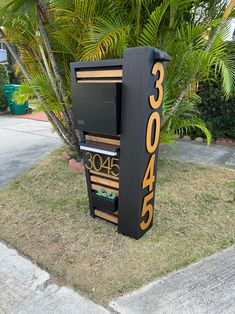 a black and gold sign sitting on the side of a road next to a tree