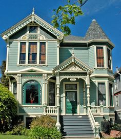 an old victorian style house with green paint and white trim on the front porch, stairs leading up to the second floor